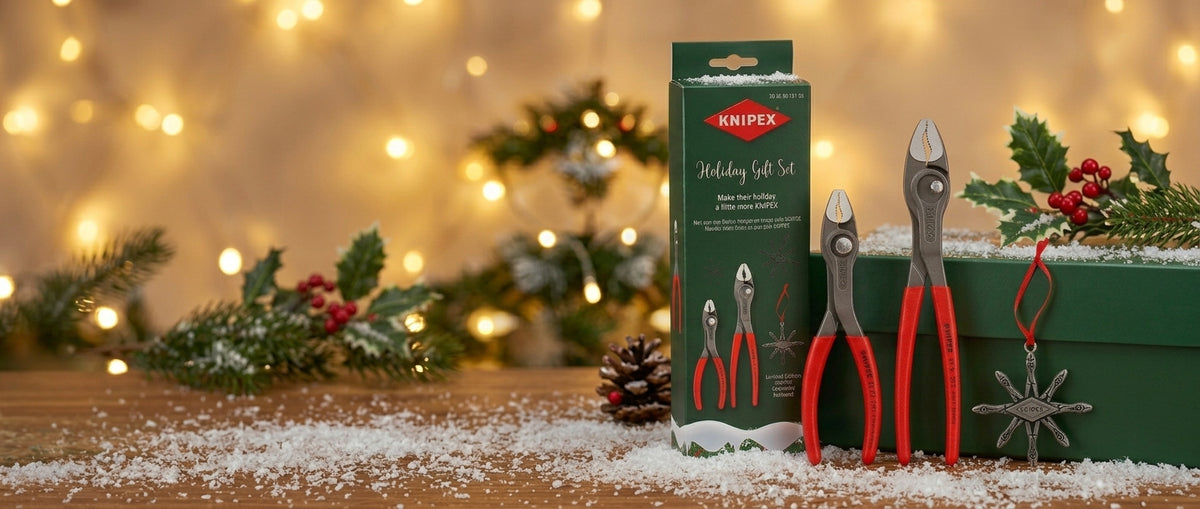 Holiday banner featuring the KNIPEX 2026 Holiday Gift Set box, TwinGrip pliers, and metal snowflake ornament displayed on a snow-dusted wooden surface with warm bokeh holiday lighting.