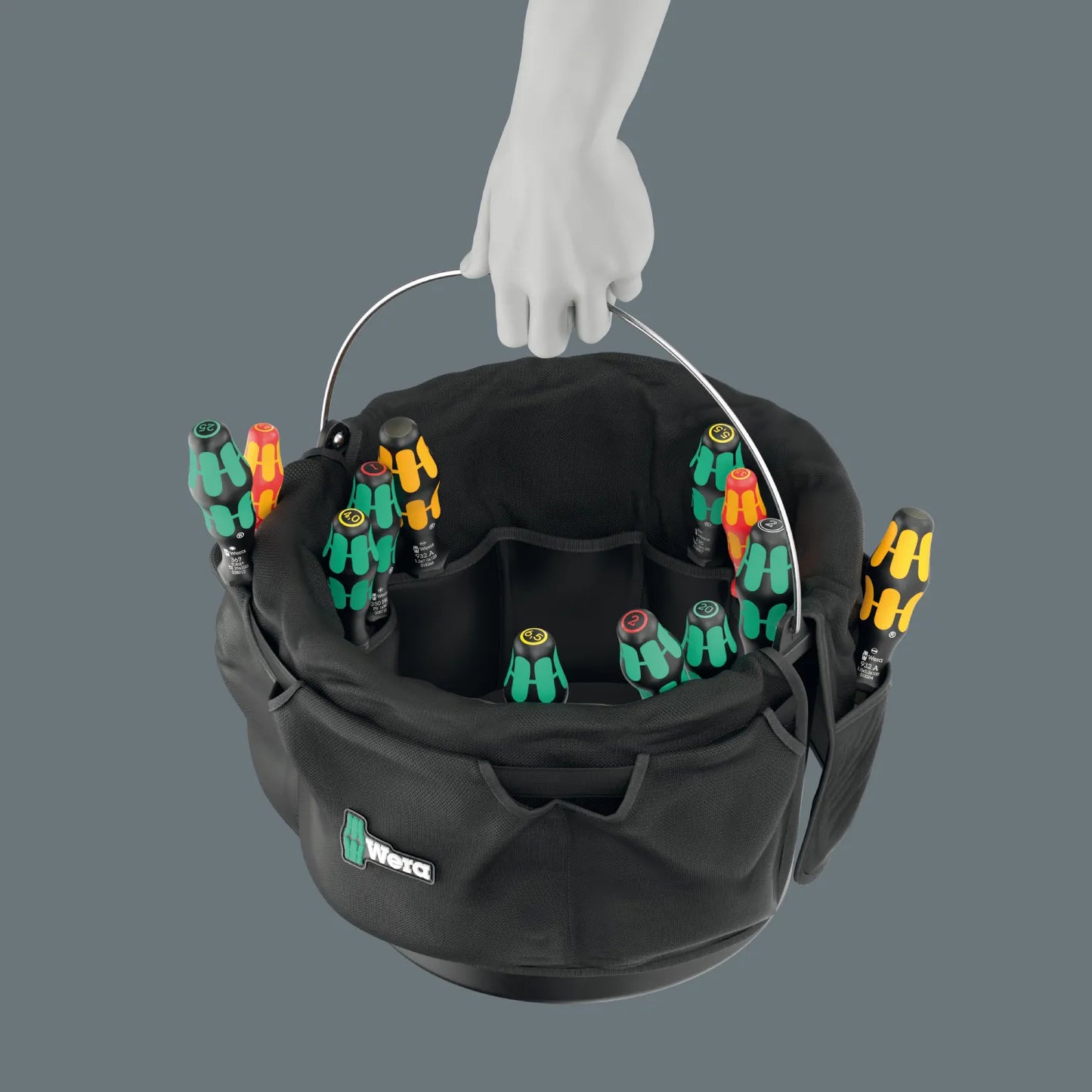 Person carrying a Wera 9559 tool bucket organizer filled with screwdrivers using the sturdy metal bucket handle.